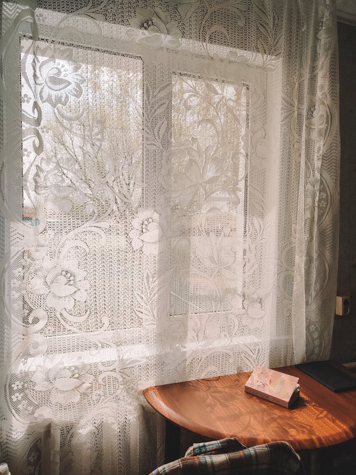 Inviting interior scene with lace curtains and warm sunlight filtering through.